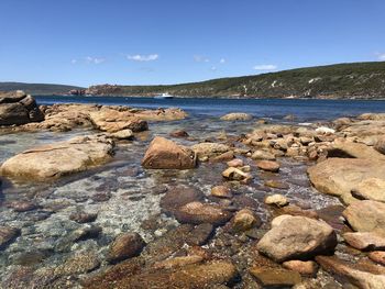 Rocks on beach against blue sky