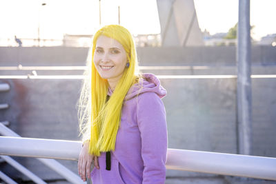 Portrait of smiling young woman against railing