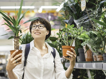 Woman chooses plants for home. shelves with seedlings, flowering plants and seeds in flower shop.