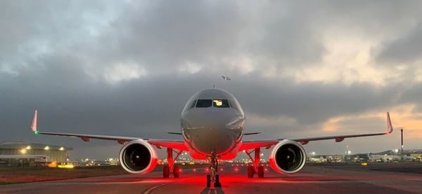 Airplane on runway against sky at dusk