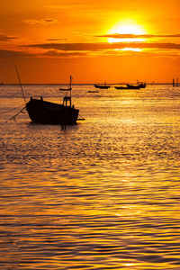 Silhouette sailboat in sea against sky during sunset