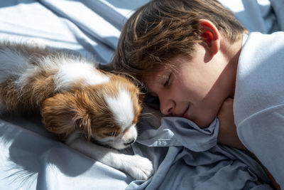 Close-up of boy with dog.  puppy cavalier in bed