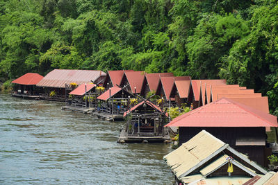 Stilt house by river amidst trees in forest