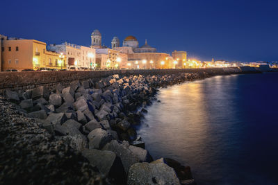 Buildings by sea against clear sky