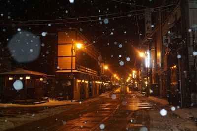 Illuminated street in city during winter at night