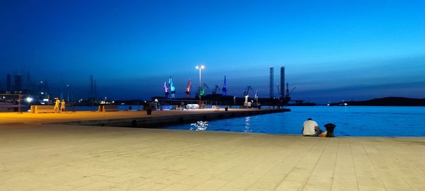 People at beach against clear blue sky at dusk