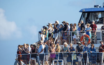 Low angle view of people standing at cruise ship against sky