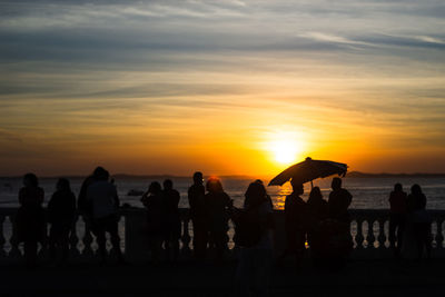 Silhouette of people enjoying the wonderful colorful sunset of farol da barra in salvador, bahia.