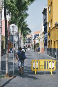 Man walking on road along buildings