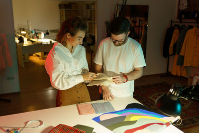 Dressmakers choosing cloth fabric for clothes collection. seamstress female talking to designer man