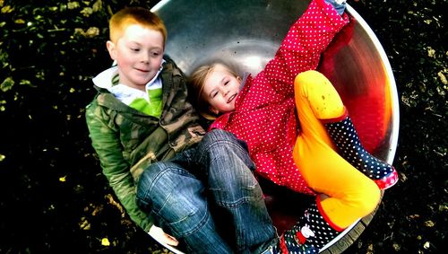 High angle view of cute siblings relaxing in container