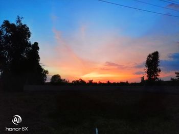 Silhouette trees on field against sky at sunset