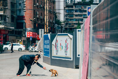 Man playing with dog on footpath