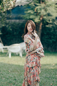 Young woman standing on field against trees