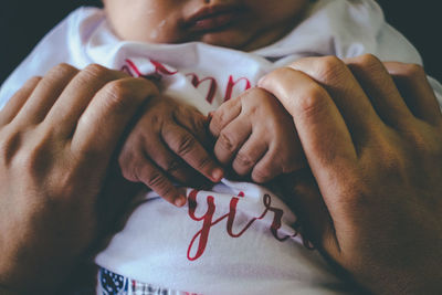 Midsection of mother holding hand of baby 