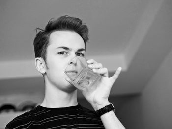 Portrait of man drinking water from glass at home