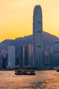 Modern buildings in city against sky during sunset