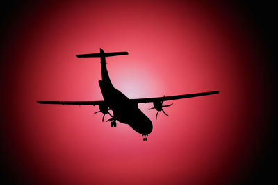 Low angle view of silhouette airplane against sky during sunset