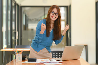 Portrait of young woman using laptop at office