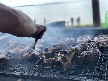 Close-up of person preparing food on barbecue grill