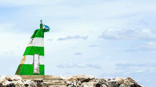 Lighthouse on rock against sky