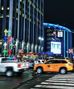 Cars on illuminated street in city at night