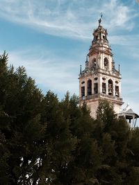 Low angle view of trees and building against sky