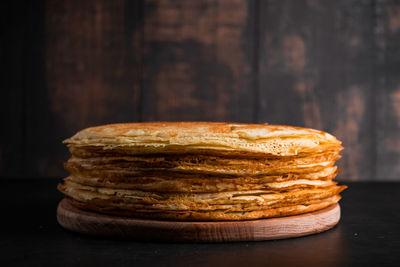 Stack of thin pancakes on dark wooden background. traditional dish of crepes for holiday maslenitsa.