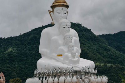 Sculpture of statue by building against sky