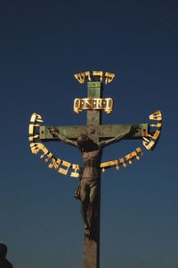 Low angle view of cross sign against clear blue sky