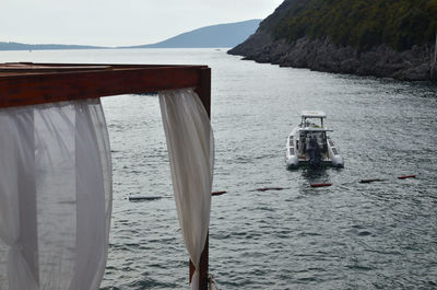 White curtains of a cabana bed and speed boats on a calm sea surface on a cloudy summer day