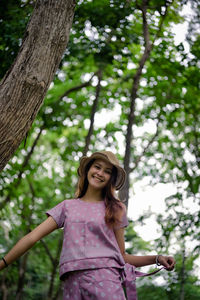 Portrait of a smiling young woman against tree trunk