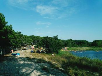 View of trees by lake against blue sky