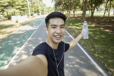 Portrait of smiling young man against trees