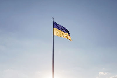 Low angle view of flag against blue sky