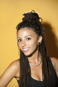 Portrait of young woman against yellow background