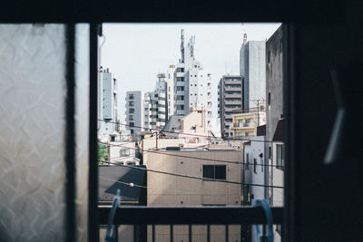 Buildings in city against sky seen through window