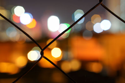 Close-up of chainlink fence against lens flare