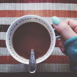 Cropped image of woman holding hot chocolate on table