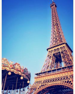 Low angle view of carousel and eiffel tower against clear blue sky