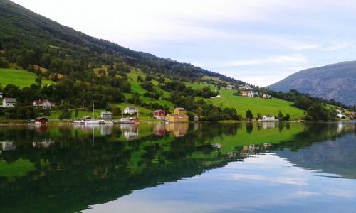 Scenic view of town by lake and mountains against sky