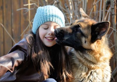 German shepherd licking face of cute smiling girl