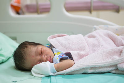 Close-up of cute newborn sleeping on bed at hospital