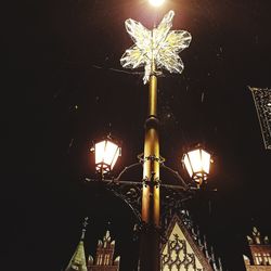 Low angle view of illuminated street light against building at night