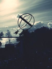 Silhouette basketball hoop on field against sky at sunset