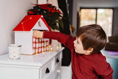 Cute boy decorating model house at home