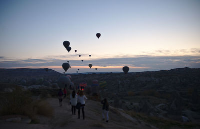 People on hot air balloon against sky during sunset