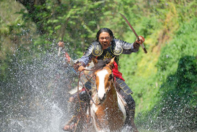 Full length of warrior riding horse in water