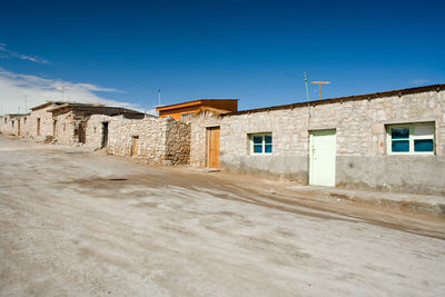 Empty road amidst buildings against blue sky