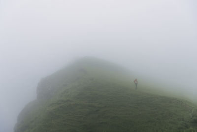 High angle view of hiker standing on hill during foggy weather